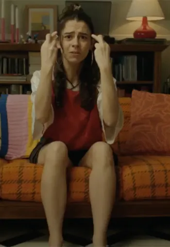 Woman sat on sofa with fingers crossed.