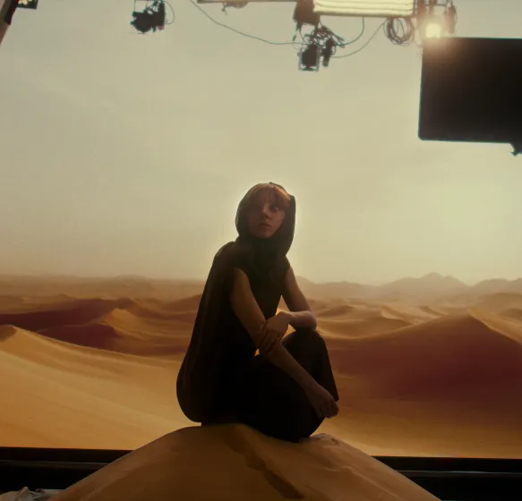 A woman on a sand dune with a green screen background during a VP shoot